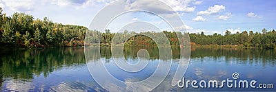 Calm lake surrounded by trees panorama Stock Photo