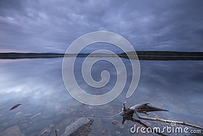 Calm lake at twilight, wood in the foreground Stock Photo