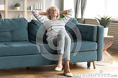 Calm mature 50s woman rest on comfortable sofa Stock Photo