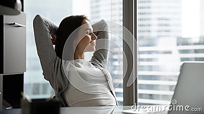 Calm millennial businesswoman dreaming sitting at desk in relaxed pose Stock Photo