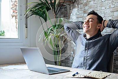 Calm millennial man in glasses sit relax at home office workplace take nap or daydream. Happy relaxed Caucasian young male rest in Stock Photo
