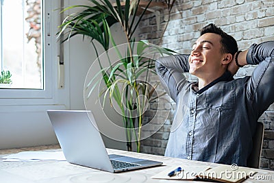 Calm millennial man in glasses sit relax at home office workplace take nap or daydream. Happy relaxed Caucasian young male rest in Stock Photo