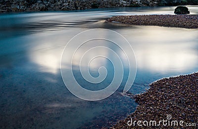 Calm shimmering mountain river with red pebbles Stock Photo