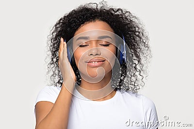 Calm peaceful African American woman in headphones enjoying music Stock Photo