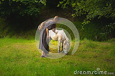 Calm peaceful fairy tale photography tender woman with pony in green grass meadow on forest edge in spring clear weather day Stock Photo