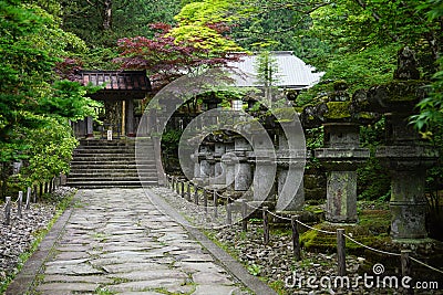 Calm and peaceful green Japanese garden with small stony statues, steps and temple as a symbol of harmony, balance and relaxation Stock Photo