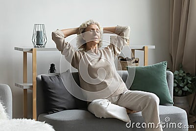 Calm peaceful middle aged mature hoary woman relaxing on cozy couch. Stock Photo