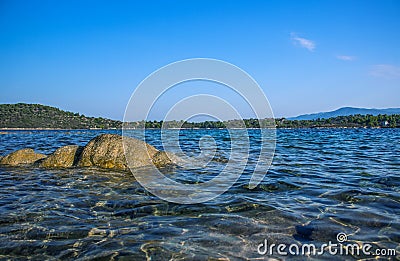 Calm and peaceful natural scenic landscape background of lake waterfront with shallow water and stones on bottom Stock Photo