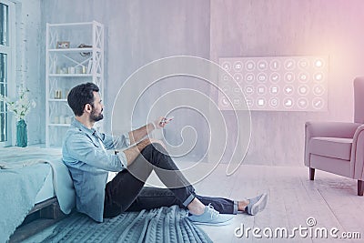 Calm programmer using remote control while sitting at home Stock Photo