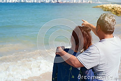 Calm and relaxed mature couple cuddling standing on the beach during the summer Stock Photo