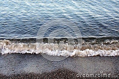 Small Waves Rolling on Dark Sand Beach Stock Photo