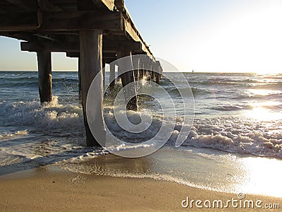 Calm sea waves under a wooden plank jetty in Seaford, VIC, Australia Stock Photo