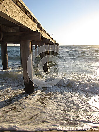 Calm sea waves under a wooden plank jetty in Seaford, VIC, Australia Stock Photo