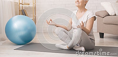 Calm senior lady practicing yoga, meditating at home Stock Photo