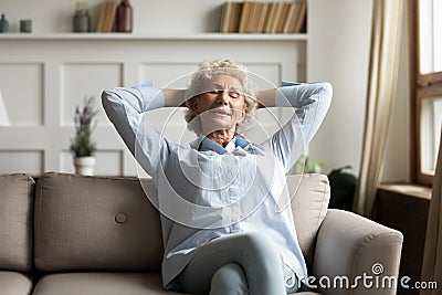 Calm senior woman relax on couch in living room Stock Photo
