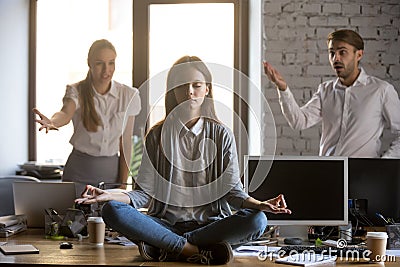 Calm serene employee meditating in office ignoring annoying coll Stock Photo