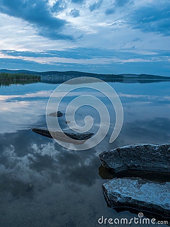 Calm, serenity, meditation concept. Sunset on the lake, stones in the water in the foreground, quiet water, cloudless sky Stock Photo