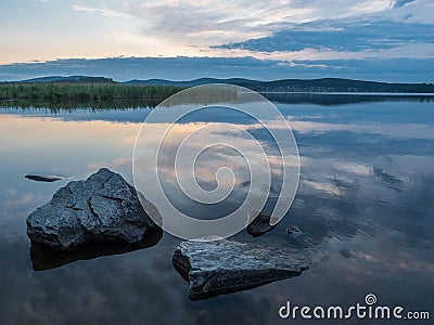 Calm, serenity, meditation concept. Sunset on the lake, stones in the water in the foreground, quiet water, cloudless sky Stock Photo