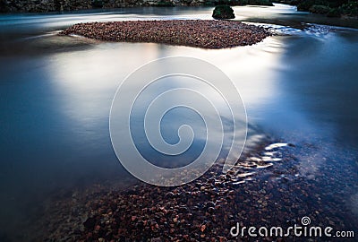 Calm shimmering mountain river with red pebbles Stock Photo