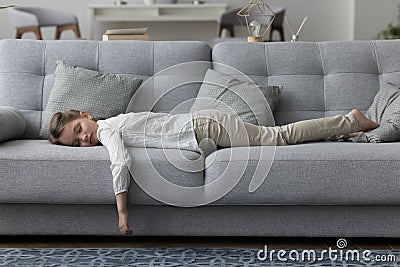 Calm sleepy little kid girl lying on belly on couch Stock Photo