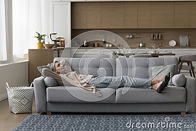 Calm sleepy mature lady lying on sofa with closed eyes Stock Photo
