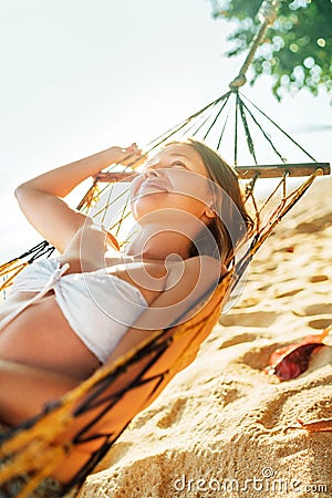 Calm smiling young woman lying in hammock in bright sun light Stock Photo