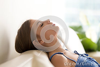 Calm young woman relaxing on cozy sofa, breathing fresh air Stock Photo