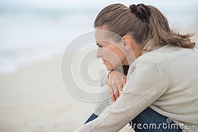 Calm young woman sitting on cold beach Stock Photo