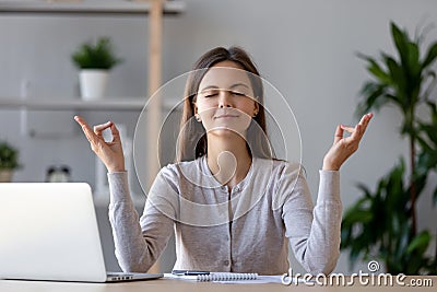 Calm young woman taking break doing yoga exercise at workplace Stock Photo