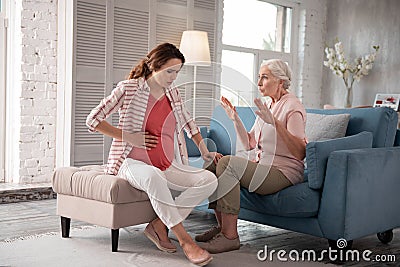 Caring mother calming her pregnant daughter having ache Stock Photo