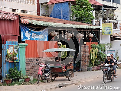 Little Asian girl plays in a motor rickshaw, a scooter rides along the road Editorial Stock Photo