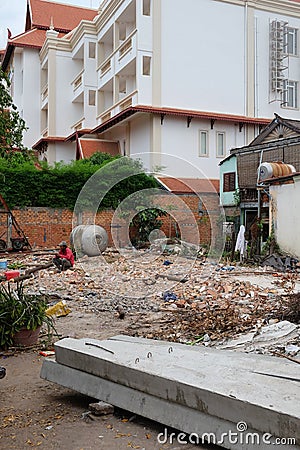 Cambodia, Siem Reap 12/08/2018 a man in a red shirt sitting on a pile of construction waste Editorial Stock Photo