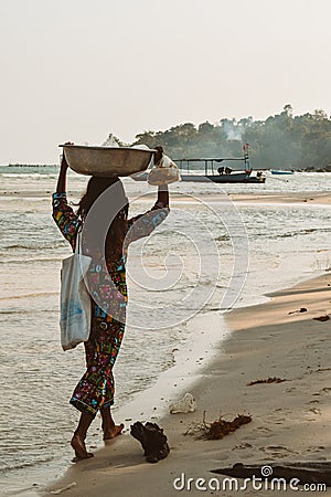 Cambodian girl carrying a basket with goods on a beach of the Koh Rong Island in Cambodia Editorial Stock Photo
