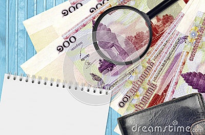 100 Cambodian riels bills and magnifying glass with black purse and notepad. Concept of counterfeit money. Search for differences Stock Photo