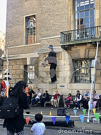 Cambridge, UK - April 20, 2019: Man doing tightrope walking, also called funambulism, in the Cambridge Market Square Editorial Stock Photo