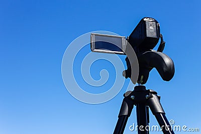 Camcorder on a tripod against a clear blue sky Stock Photo