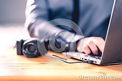 Camera connected to laptop with usb cable. Man editing photos with computer software. Photographer transfer files to computer. Stock Photo