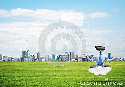 Camera headed man sitting in lotus pose on cloud against modern cityscape Stock Photo