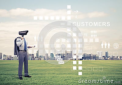 Camera headed man standing on green grass against modern cityscape Stock Photo