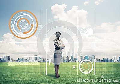 Camera headed woman standing on green grass against modern cityscape Stock Photo