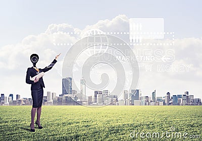 Camera headed woman standing on green grass against modern cityscape Stock Photo