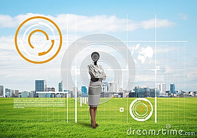 Camera headed woman standing on green grass against modern cityscape Stock Photo