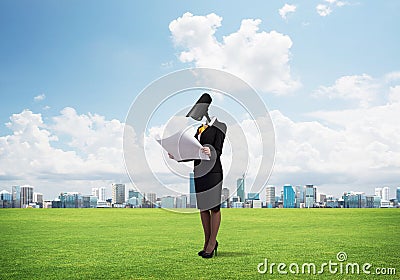 Camera headed woman standing on green grass against modern cityscape Stock Photo