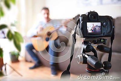 Camera recording video blogger doing review of guitar at home Stock Photo