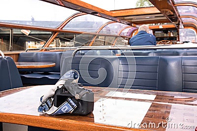 Camera on table by interior seating inside a glass roofed sightseeing canal cruise trip boat for tourists Editorial Stock Photo