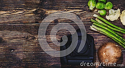 Camera and vegetables on wooden background, as a concept of food photography. Creative conceptual picture for professional dishes Stock Photo