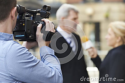 Cameraman Recording Female Journalist Interviewing Businessman Stock Photo