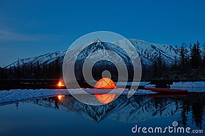 Camp near the mountain lake. Night landscape with a tent near the water. Stock Photo
