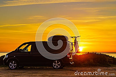 Camper with bicycles on rack camping on beach at sunrise Stock Photo