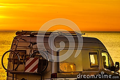 Camper with bicycles on rack camping on beach at sunrise Stock Photo